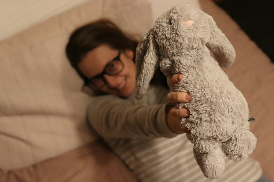woman in gray sweater holding white bear plush toy