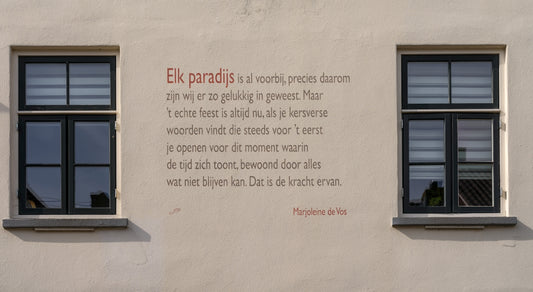 A poem is written on a wall between two windows.