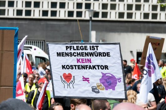 Protest sign: care is human dignity, not a cost factor
